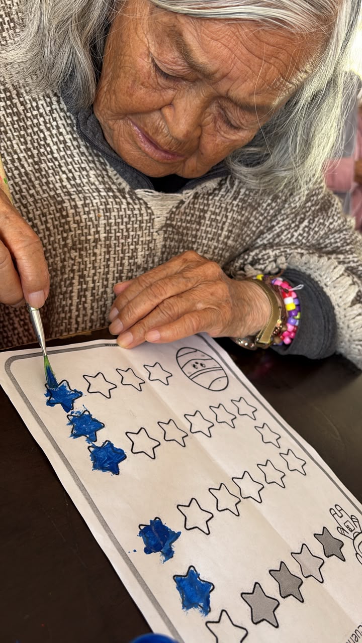 Residente pintando estrellas azules en una actividad manual