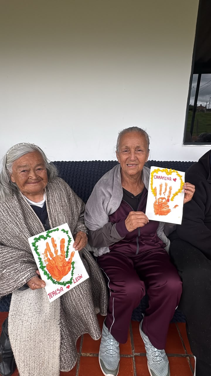 Dos residentes sonrientes mostrando sus manualidades de manitas pintadas